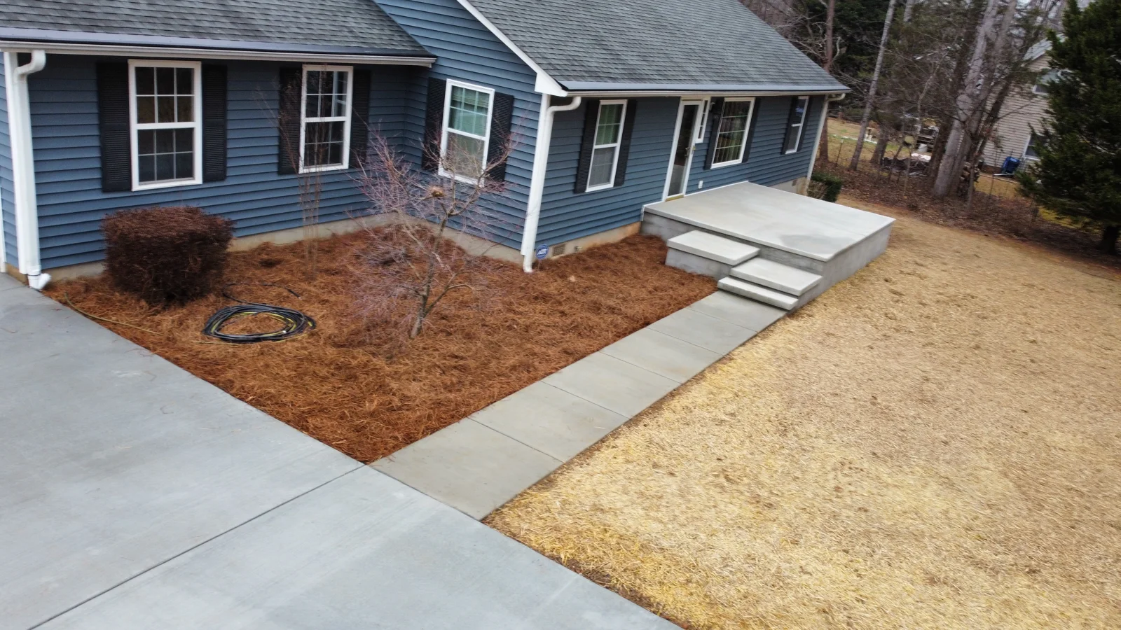 Concrete entry steps, walkways and driveway at a blue home