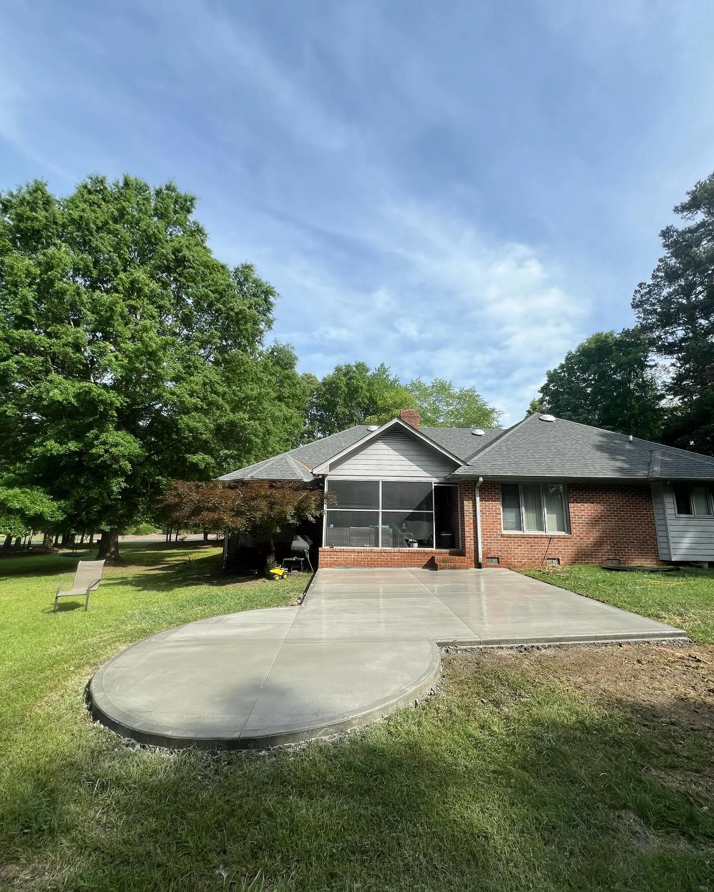 Curved concrete patio behind a brick home