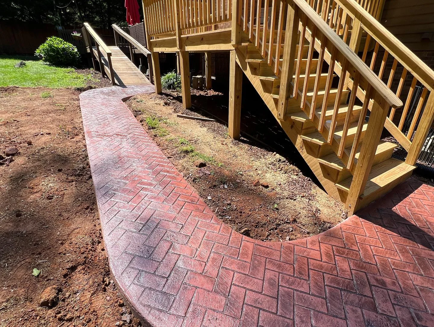 Red patterned concrete path curving beside timber steps