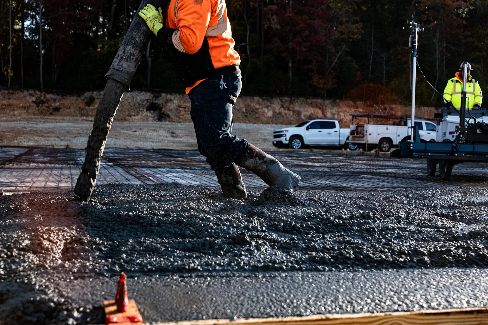 Crew member placing fresh concrete across reinforcement