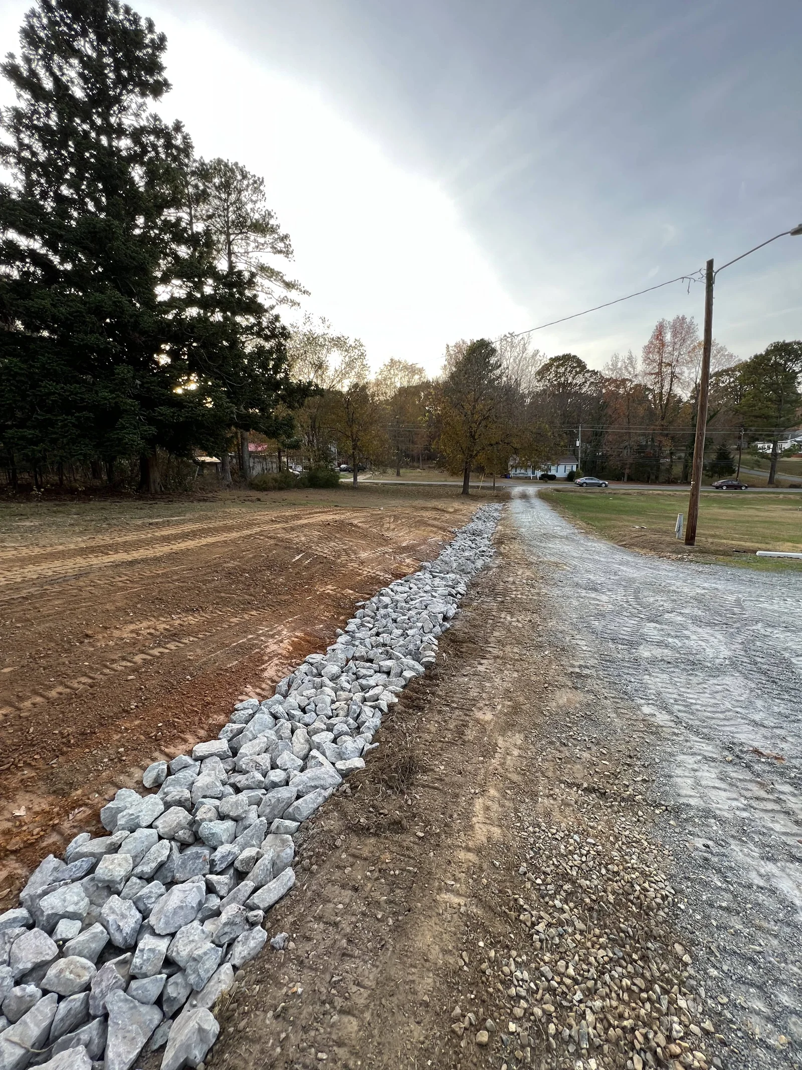 Rock-lined drainage channel following a gravel driveway