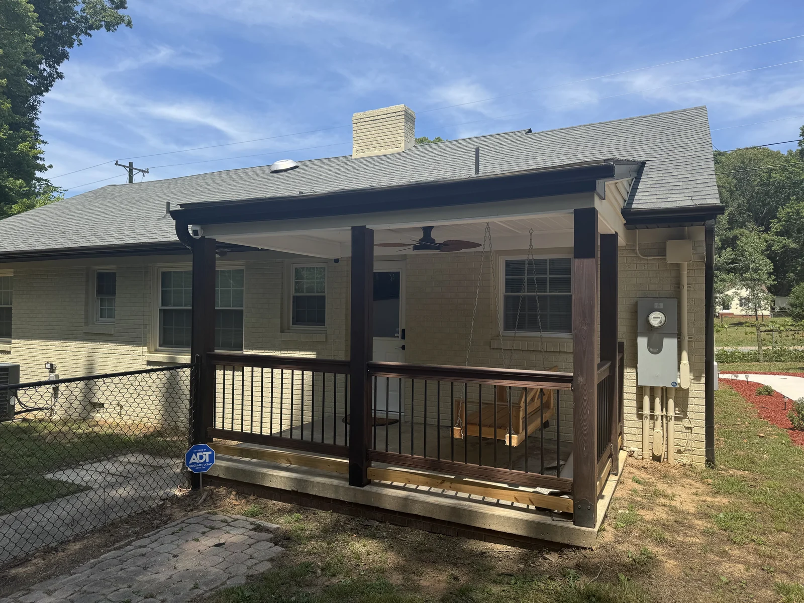 Screened porch with a white door and timber railing on a brick home